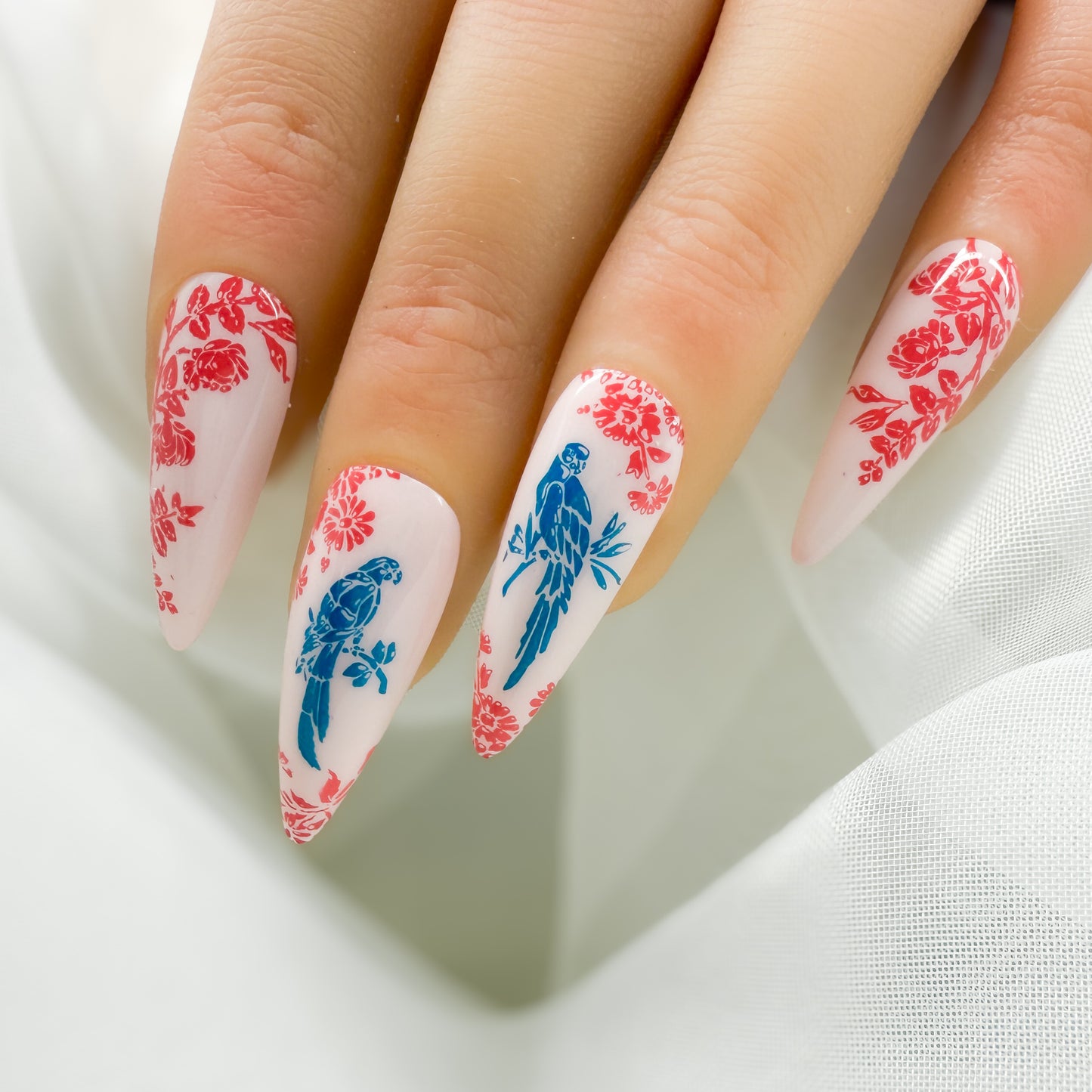 Nails with floral and parrot design on a white background