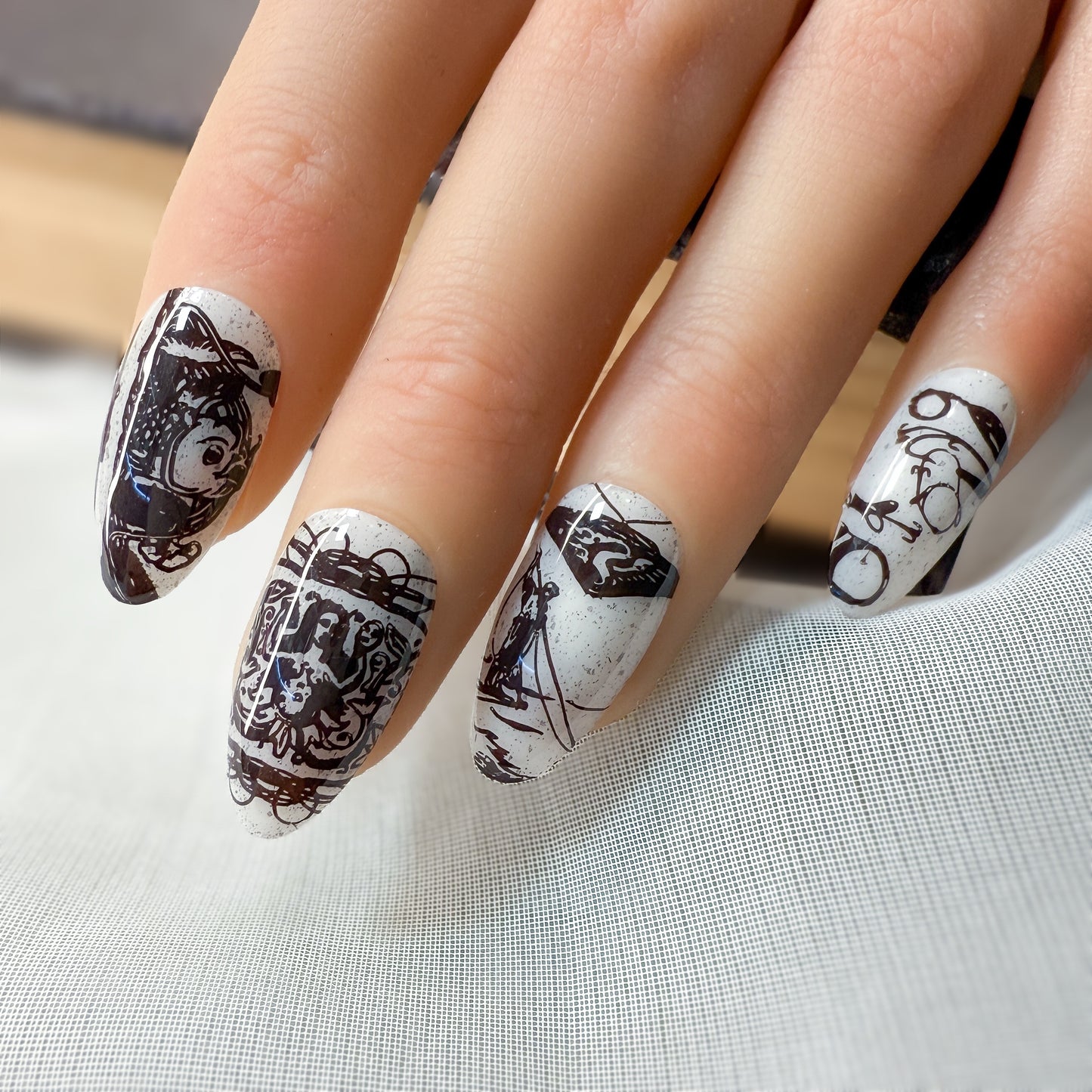 Nails with black and white artistic designs on a light gray background