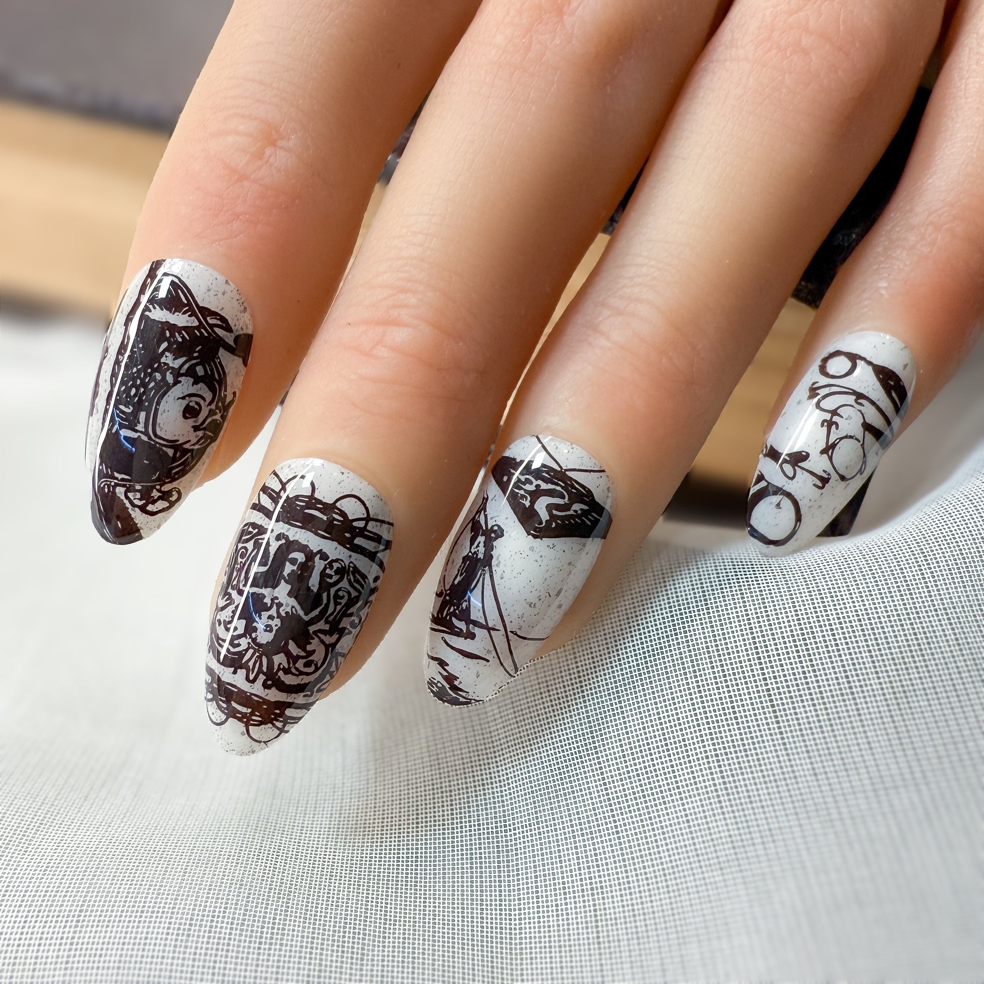 Nails with black and white artistic designs on a light gray background