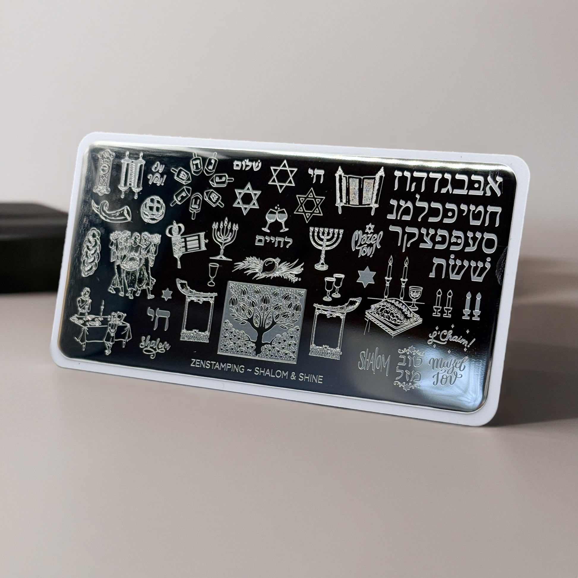 Rectangular stamping plate with Hebrew text and religious symbols on a gray surface