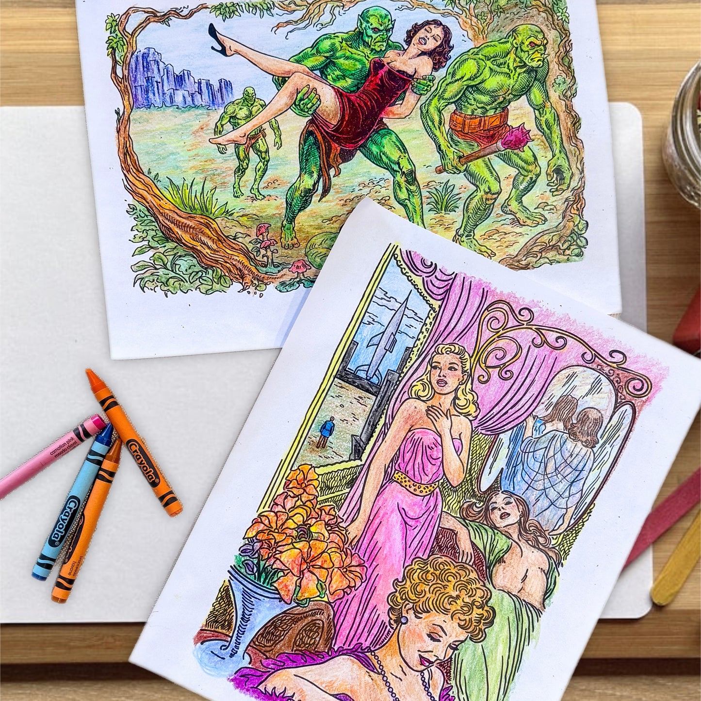 Coloring book pages filled in with crayon resting on a tabletop