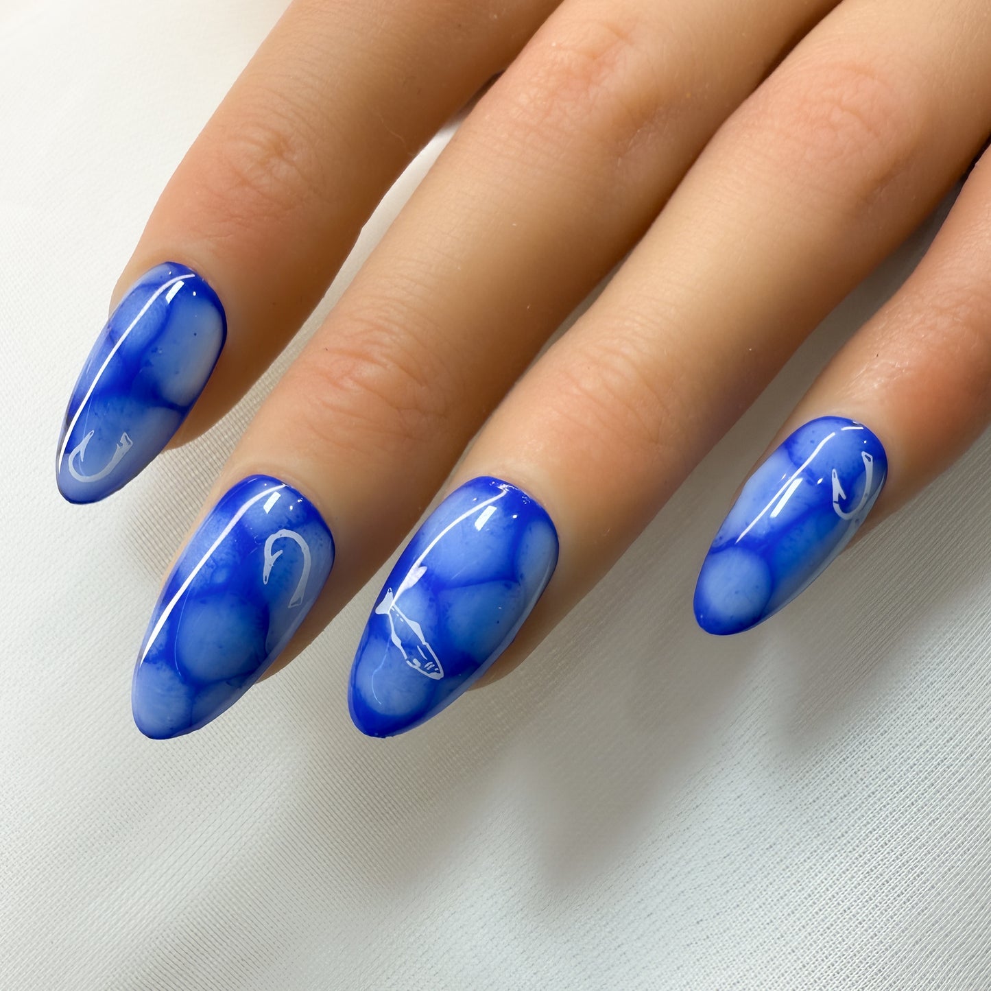 Hand with blue marbled nail polish on a light background