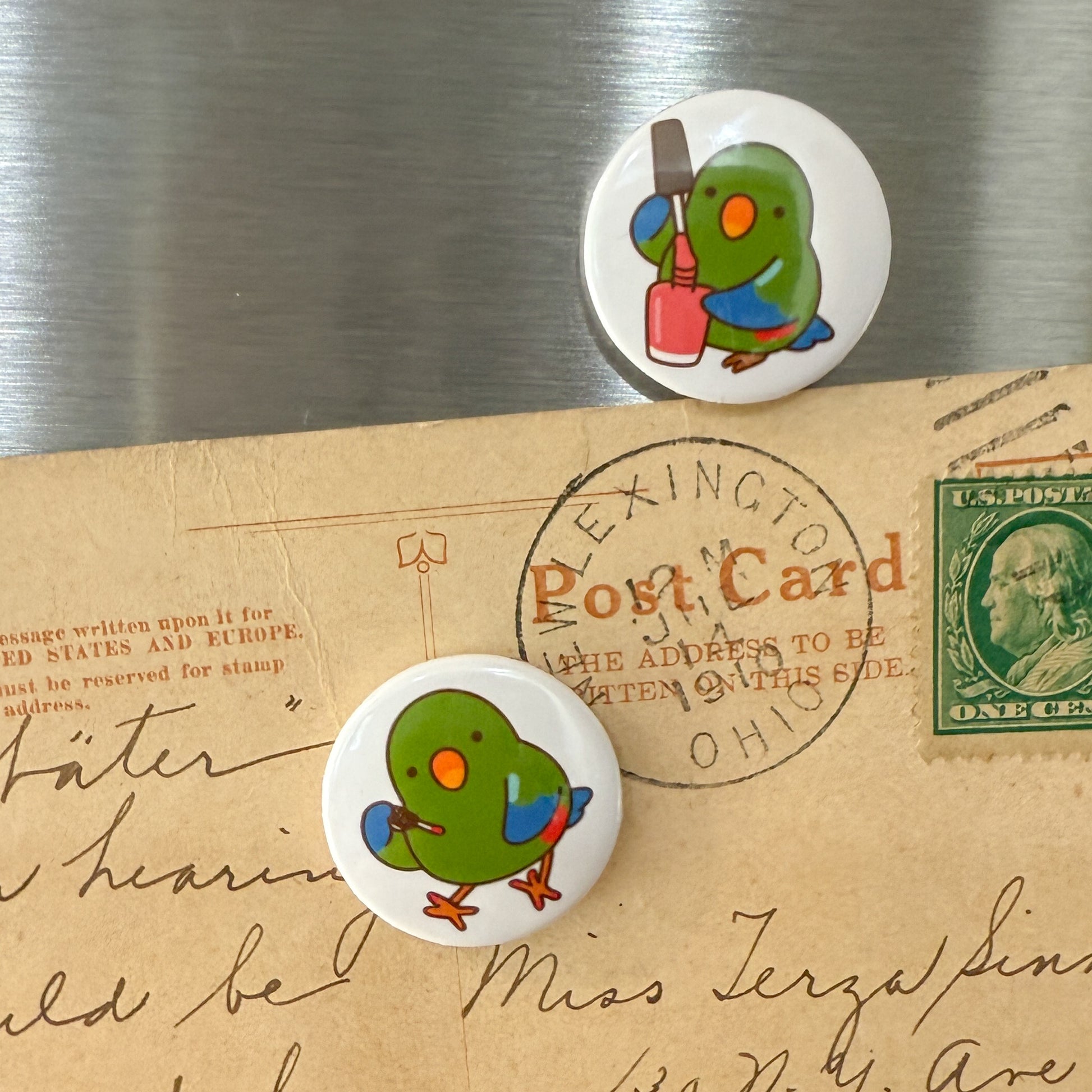 Two green bird buttons on an old postcard with a stamp.